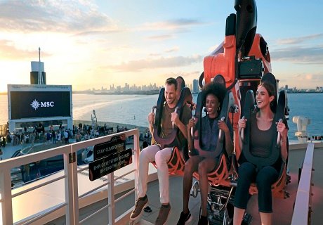 Guests enjoying a thrilling ride on an MSC cruise ship with a city skyline at sunset in the background | MSC Cruises Guests enjoying a thrilling ride on an MSC cruise ship with a city skyline at sunset in the background | MSC Cruises
