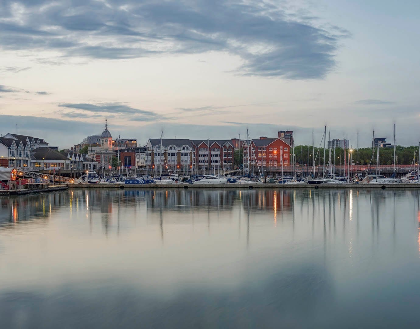 A marina with sailboats and waterfront buildings at dusk | MSC Cruises A marina with sailboats and waterfront buildings at dusk | MSC Cruises
