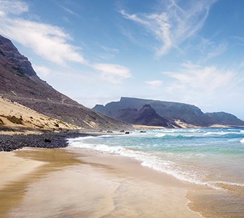 A beautiful beach with crystal-clear water and mountains in the background | MSC Cruises