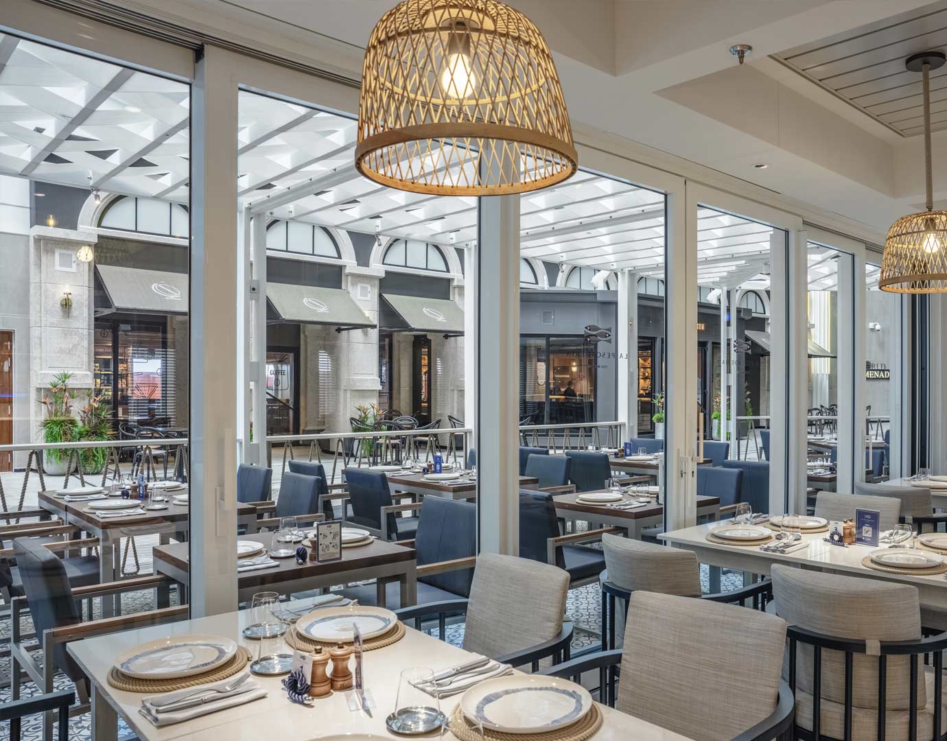 Elegant dining area with set tables and a view of a stylish promenade | MSC Cruises Elegant dining area with set tables and a view of a stylish promenade | MSC Cruises