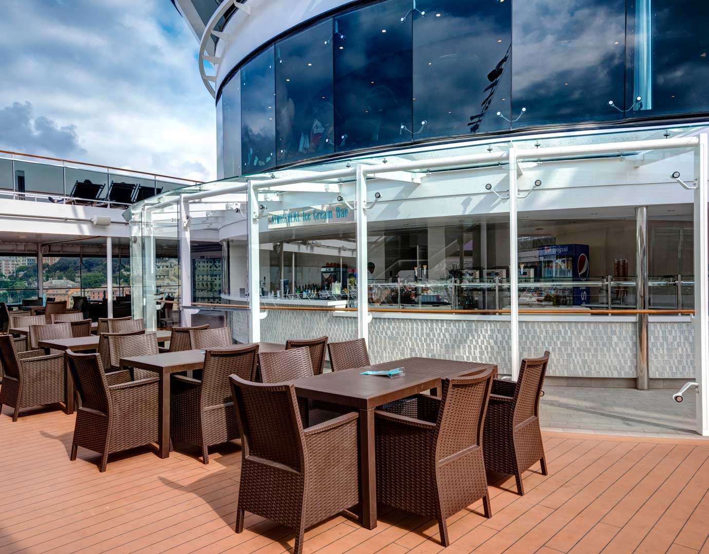 Outdoor dining area with wicker chairs and tables near an ice cream bar on an MSC cruise ship | MSC Cruises Outdoor dining area with wicker chairs and tables near an ice cream bar on an MSC cruise ship | MSC Cruises