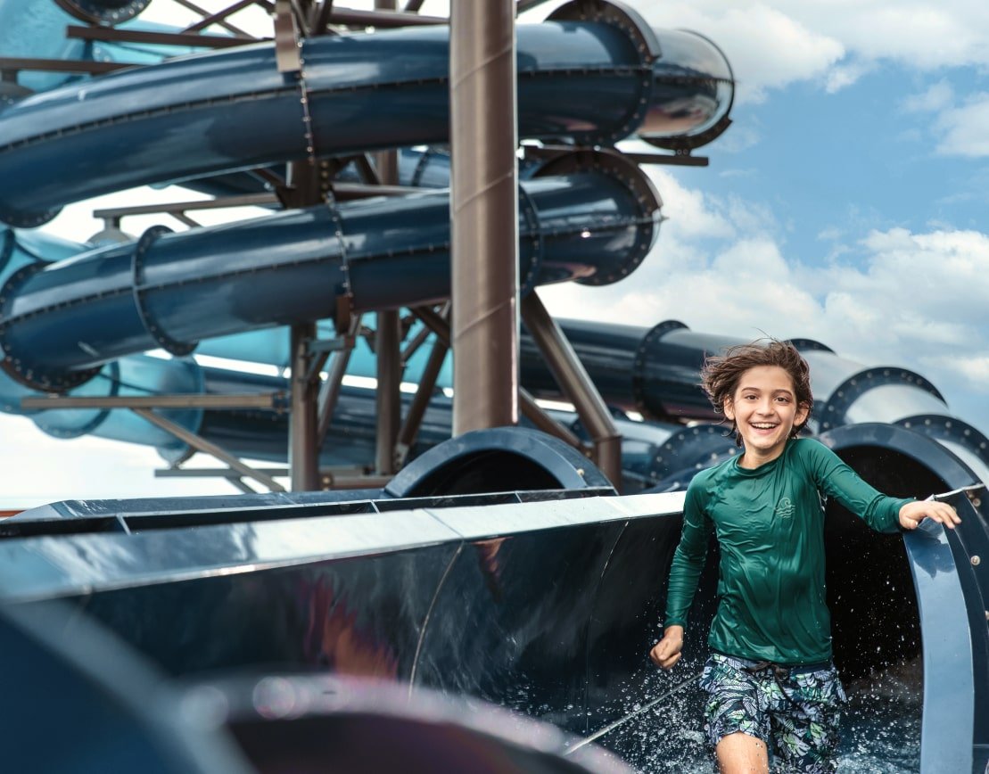 Young boy smiling as he leaves a spiraling water slide on a MSC Cruises cruise ship.