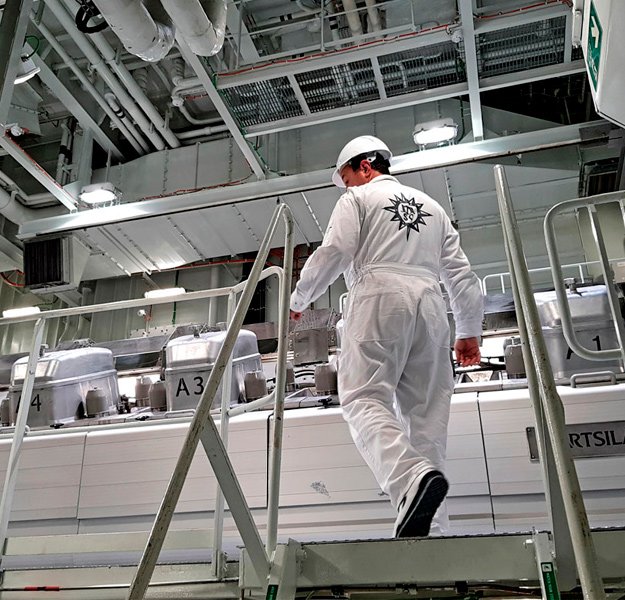 An engineer in uniform walking up steps in the engine room of a cruise ship | MSC Cruises