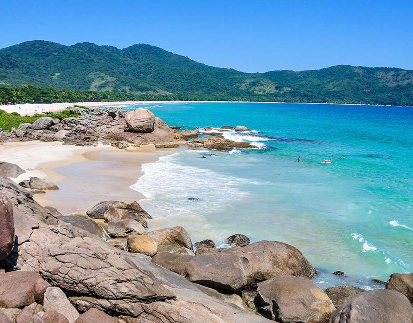 A pristine tropical beach with turquoise waters and lush green hills | MSC Cruises