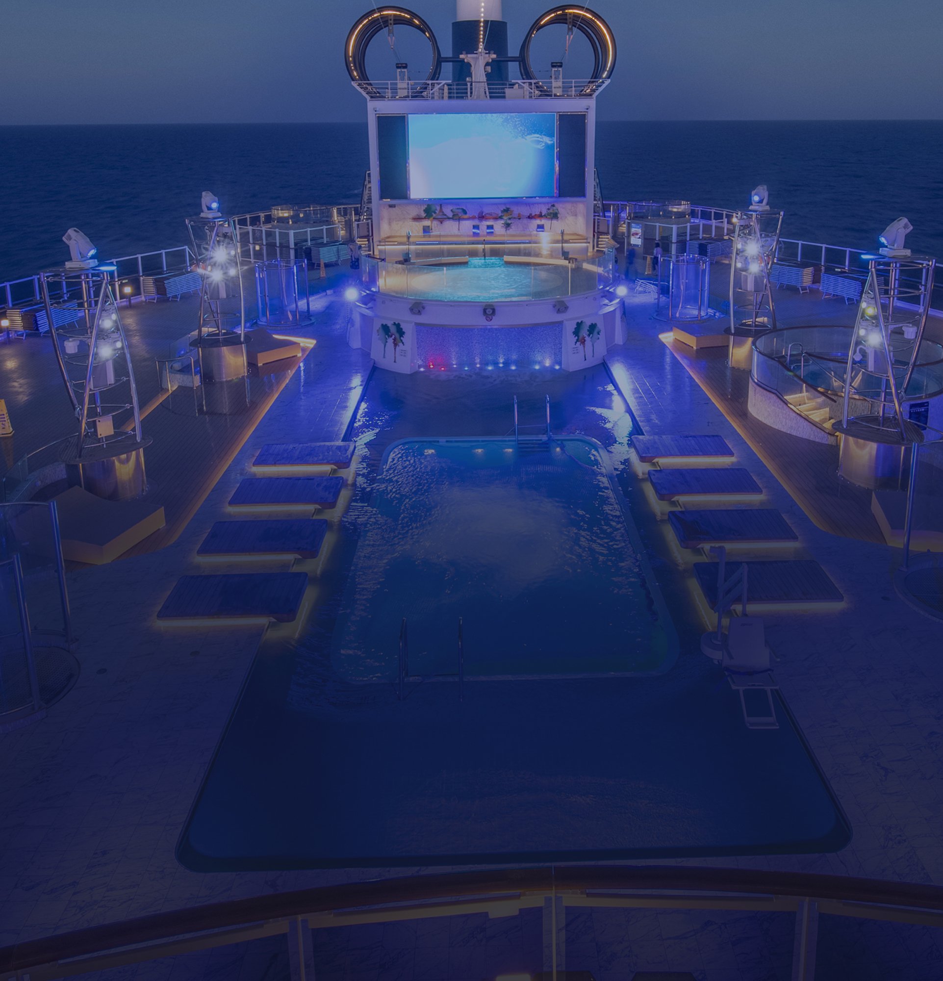 Illuminated cruise ship pool deck with lounge chairs and a large movie screen at night | MSC Cruises