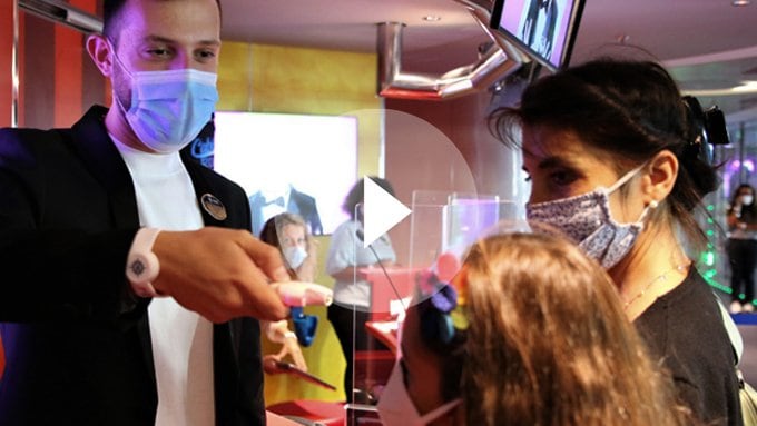 Crew member assisting a child with a wristband in a vibrant onboard setting | MSC Cruises Crew member assisting a child with a wristband in a vibrant onboard setting | MSC Cruises