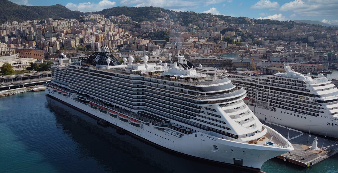 MSC Seaside docked in a scenic port city with a backdrop of hills and colorful buildings | MSC Cruises