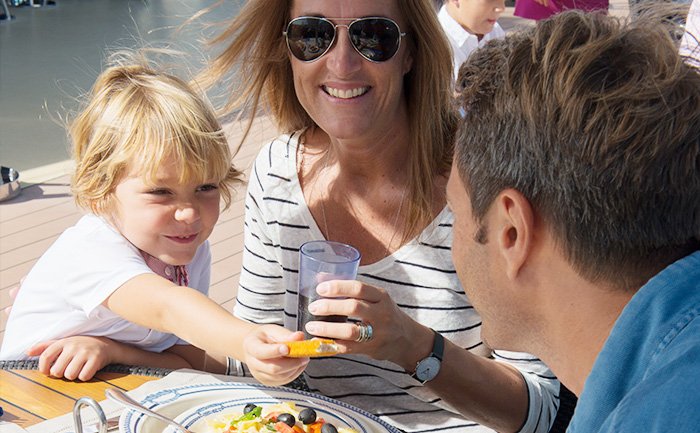 Family enjoying a meal on a sunlit cruise ship deck | MSC Cruises