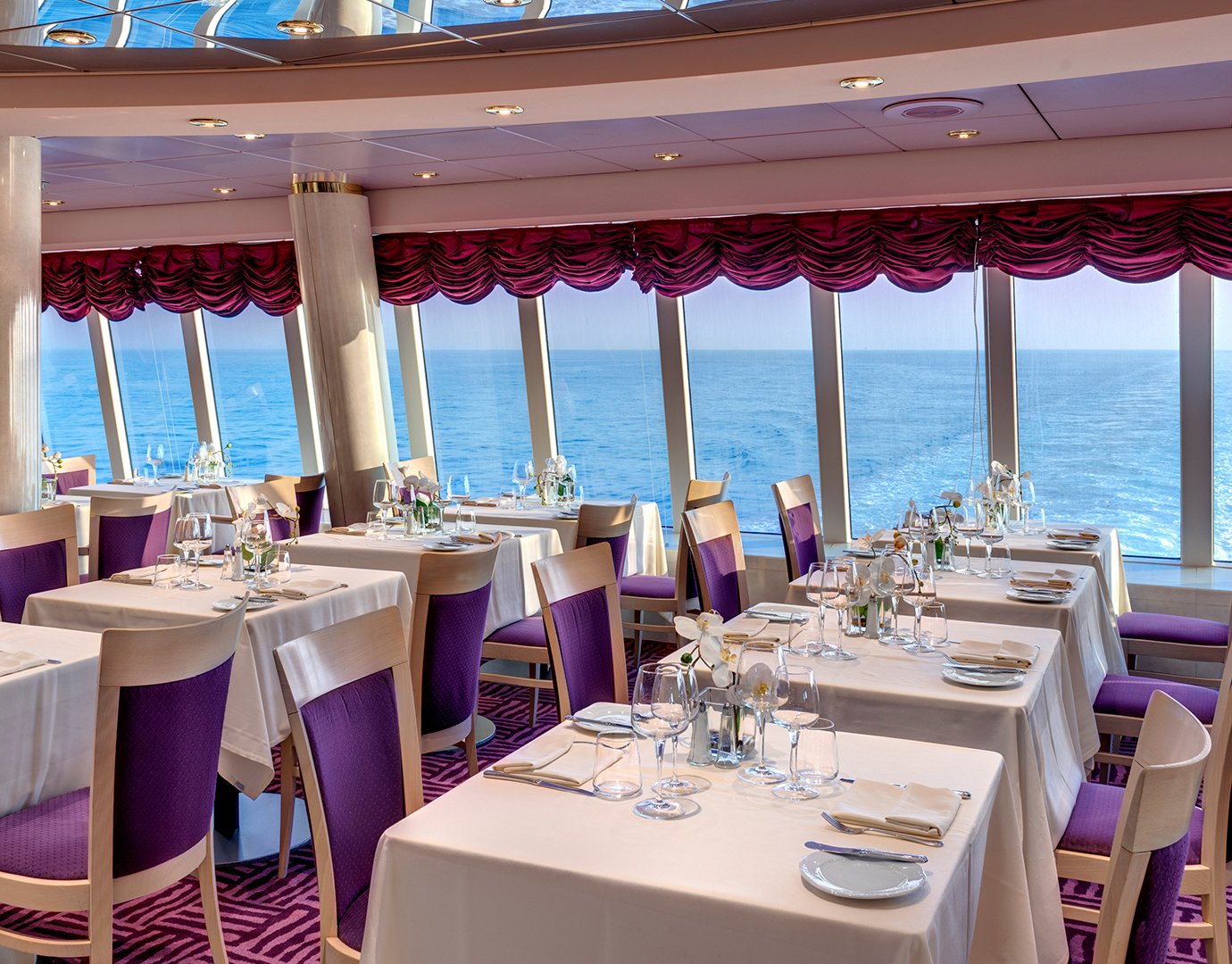 Elegant cruise ship restaurant with ocean views and purple-accented decor | MSC Cruises Elegant cruise ship restaurant with ocean views and purple-accented decor | MSC Cruises