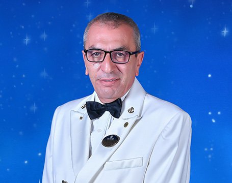 A cruise ship captain in a formal white uniform against a starry blue background | MSC Cruises A cruise ship captain in a formal white uniform against a starry blue background | MSC Cruises