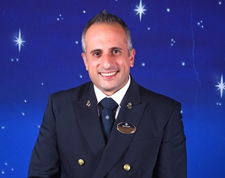 A uniformed MSC crew member against a starry backdrop | MSC Cruises A uniformed MSC crew member against a starry backdrop | MSC Cruises
